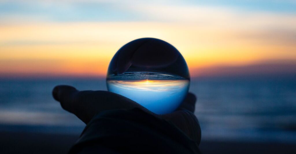 Holding a glass ball in hand with the sunset in the background
